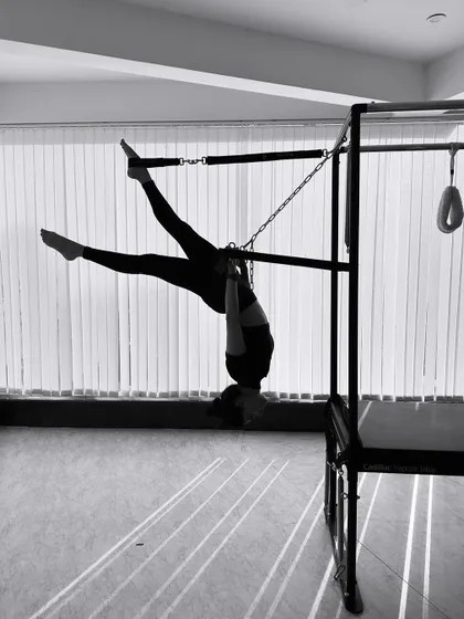 The play of light and shadow in this black and white image highlights the strength required for this inverted hanging pose.