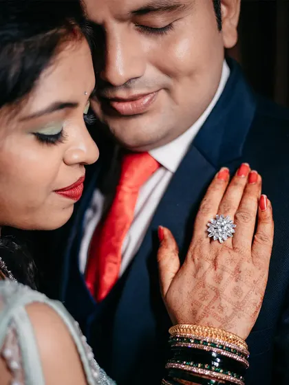 A close up focusing on the details. This shot highlights the bride-to-be's stunning engagement ring, her intricate henna, and the couple's gentle touch.