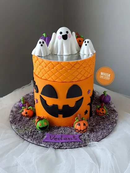 A fun and spooky rotating Halloween cake. This design features a pumpkin theme with ghosts on top that spin, creating a playful centerpiece for a Halloween party.