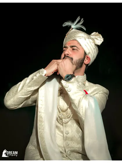 A candid shot of the groom getting ready for his wedding, looking sharp in his white sherwani.