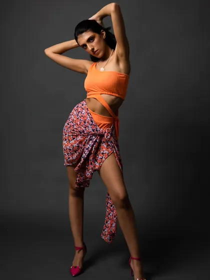 A studio shoot for a swimwear brand. The vibrant colors of the swimsuit pop against the dark grey background, and the pose is confident and powerful.