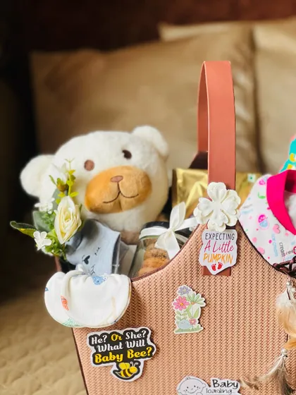 A closer view of the mom-to-be basket, showing the soft teddy bear, baby clothes, and the "Expecting a Little Pumpkin" sticker.