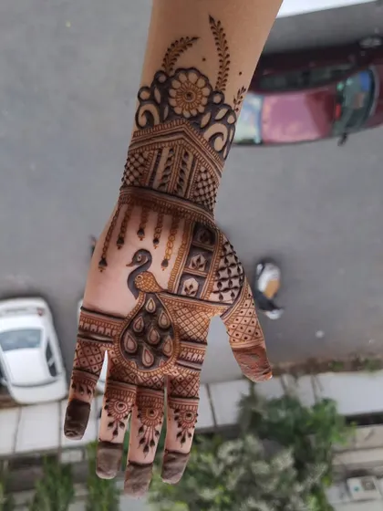 A beautiful peacock design on a single hand. The intricate feather details and the cuff at the wrist make this a standout piece.