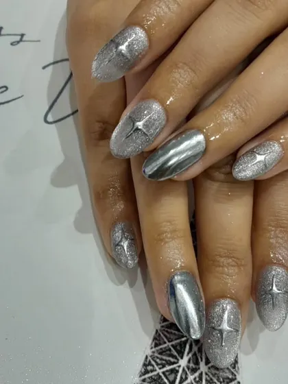 This design mixes textures for a unique look. We combined silver glitter nails with full-coverage silver chrome accent nails, all tied together with a starburst detail.