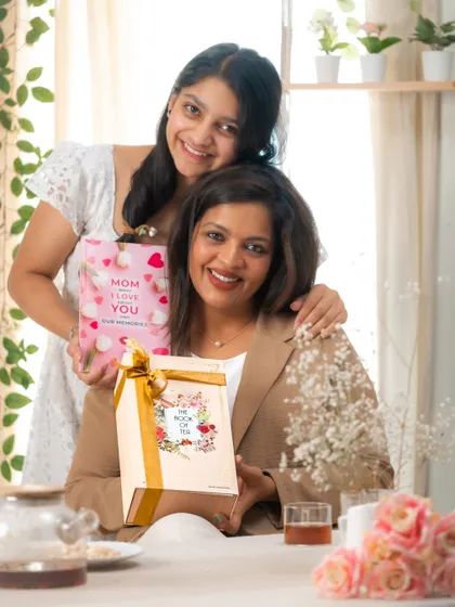 A joyful portrait of a mother and daughter sharing a special moment with their gifts. This lifestyle shot for a Mother's Day campaign focuses on genuine emotion and connection.