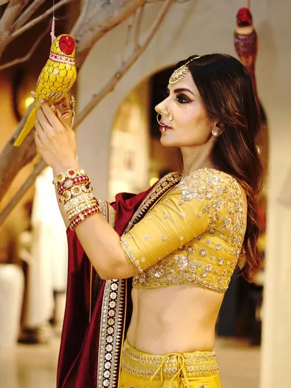 A detailed profile shot focusing on the bridal jewelry, including the maang tikka and nath, and the intricate embroidery on the blouse.