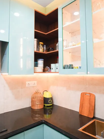 A close-up of the corner storage in the aqua-blue kitchen, showing how we utilize every inch of space. The open wooden corner shelf provides a warm contrast to the cool blue tones.