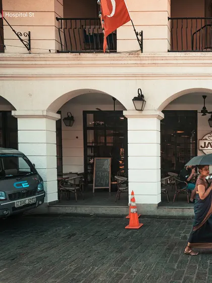 A woman in a sari walking with an umbrella on Hospital Street in Colombo. This candid shot captures a slice of daily life in the city's historic district.