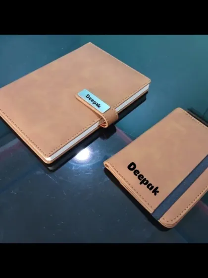 A matching tan leather set of a personalized passport holder and diary, both customized for 'Deepak'.