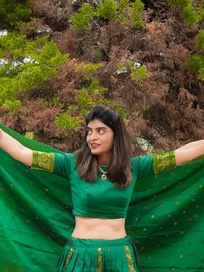 A vibrant outdoor portrait showcasing a beautiful green traditional outfit. The movement of the fabric adds a dynamic and joyful element to the photo.