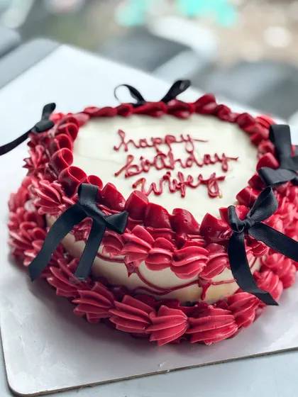 I love a good vintage buttercream and bow moment. This design features rich red buttercream piping with delicate black bows, perfect for a romantic and stylish "happy birthday wifey" cake.