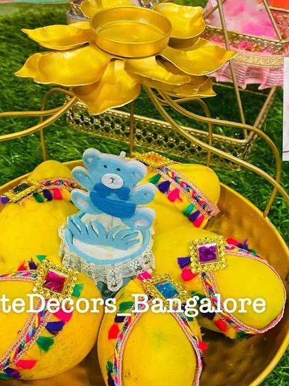 A golden basket holding decorated lemons with a blue bear cutout, perfect for a baby boy announcement or seemantham.