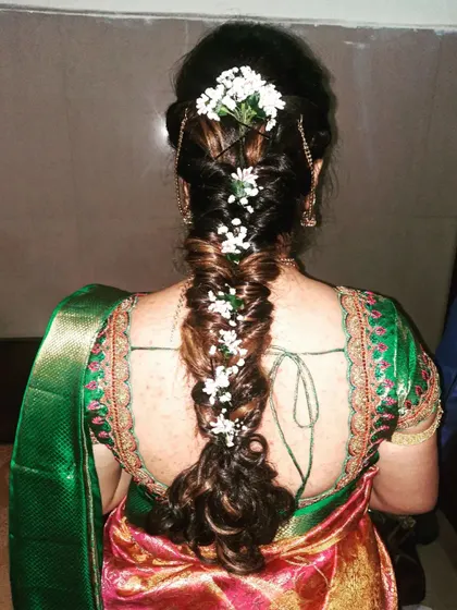 A close-up of a fishtail messy braid, intricately woven with small white flowers for a delicate and beautiful effect.