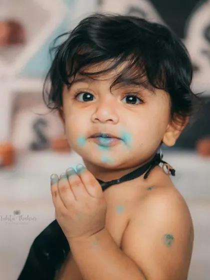 Caught with blue frosting all over his face. The messy moments are often the most memorable from a cake smash session.