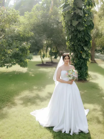 A wide shot of the bride in a beautiful garden, capturing the elegance of her gown and the serene environment.