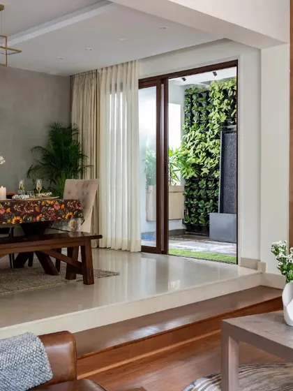 This split-level design creates a dynamic yet cohesive living and dining area. The wooden accent wall in the living nook adds warmth, while the view opens up to a vertical garden, integrating biophilic design into the home's core.
