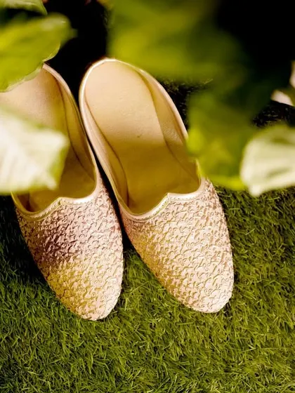 A detail shot of the groom's traditional 'juttis' resting on the grass.