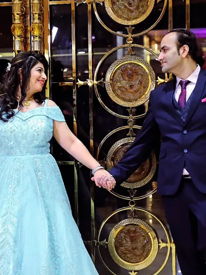 A classic engagement portrait of the couple holding hands, set against an elegant, decorative background.