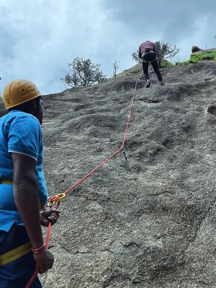 An instructor belaying a climber from below during a lead climbing practice session.