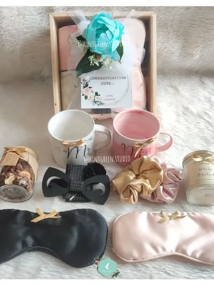 A congratulations hamper for a newly engaged or married couple. It features matching "Mr & Mrs" mugs, his and hers eye masks, and other goodies to enjoy together.