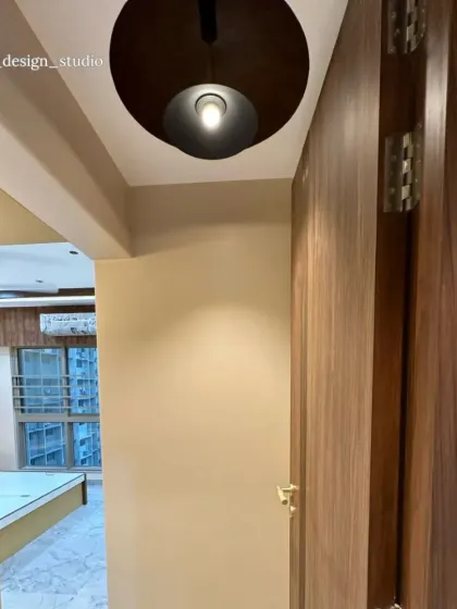 This image shows the entryway into the mustard-yellow bedroom, highlighting the warm wood tones and the modern, minimalist light fixture that greets you.