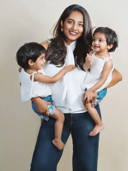 A proud mother holds her twin daughters, one in each arm. This photo is a beautiful testament to the fullness of a mother's love.