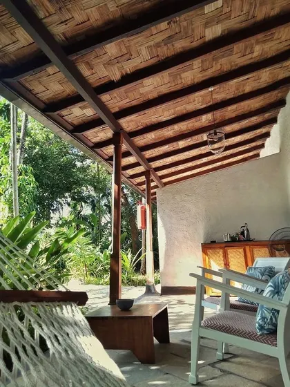 The private veranda of the Blue Room at Jalakara, featuring a woven bamboo ceiling and a comfortable hammock.