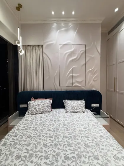 A full view of the bedroom, showcasing the 3D textured panel behind the bed, which acts as a stunning piece of wall art. The pendant lights add a touch of modern elegance.