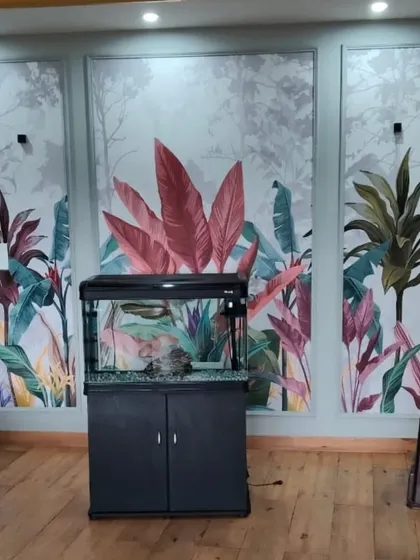 A three-panel mural depicting a lush, colorful jungle scene. This installation behind an aquarium creates a stunning and immersive backdrop that enhances the entire room.
