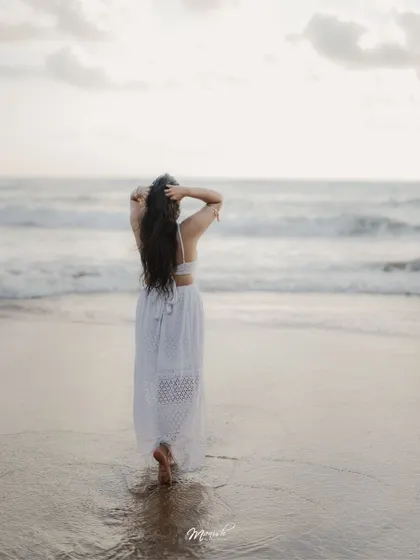 A beautiful solo portrait of the bride-to-be, looking out at the ocean, her hair blowing in the sea breeze.