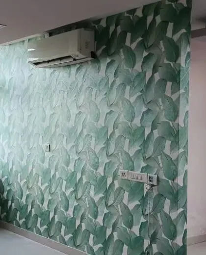 A room with a green leaf wallpaper, showing the installation process with a ladder and tools.