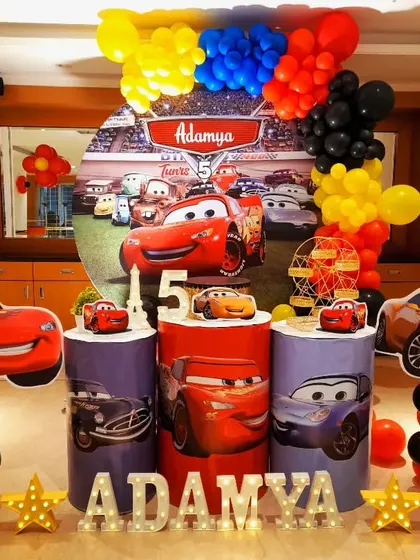 A high-speed Disney Cars theme for Adamya's 5th birthday. The decor features Lightning McQueen and friends, with a racetrack backdrop and bold, primary-colored balloons.