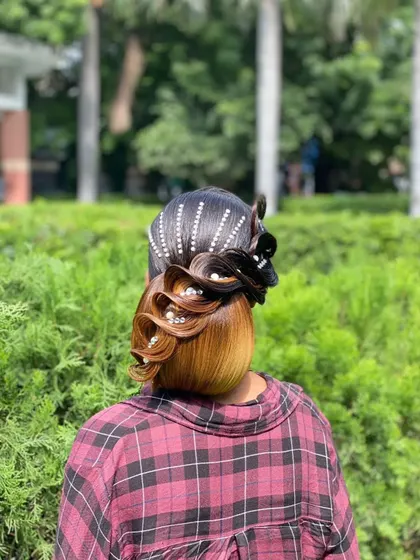 A unique and artistic updo with colored sections and pearl details, created for a photoshoot.