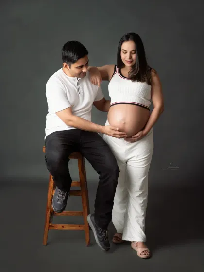 A classic couple's pose. The dad-to-be gently touches the baby bump, a simple gesture that is full of meaning and love.