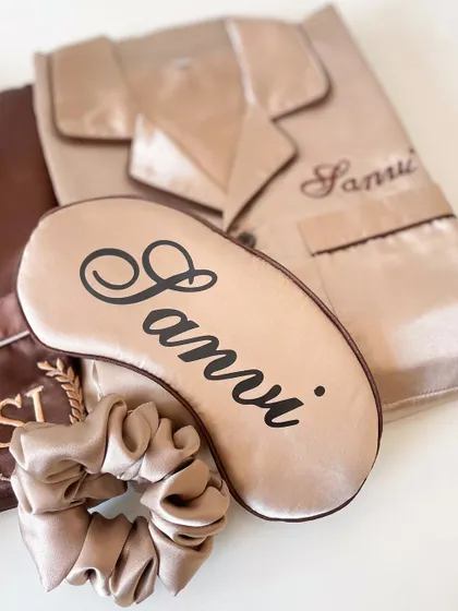 A personalized sleep set for 'Sanvi', including a satin pajama top, matching eye mask, and a scrunchie. A cozy and luxurious gift for any bridesmaid.