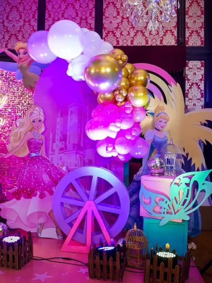 A magical corner of a Barbie and Disney Princess party, filled with pink and purple lighting, balloons, and character cutouts.