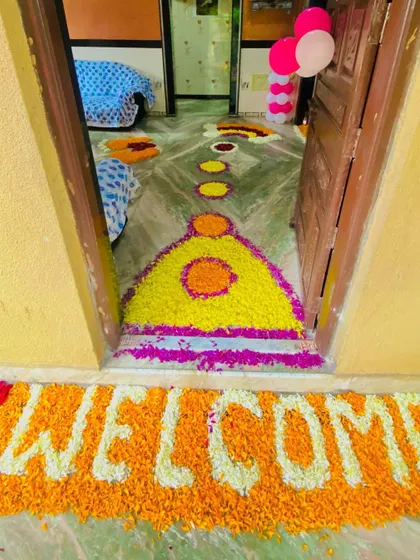 A 'WELCOME' message created with marigold flowers at the doorstep for a baby's homecoming.
