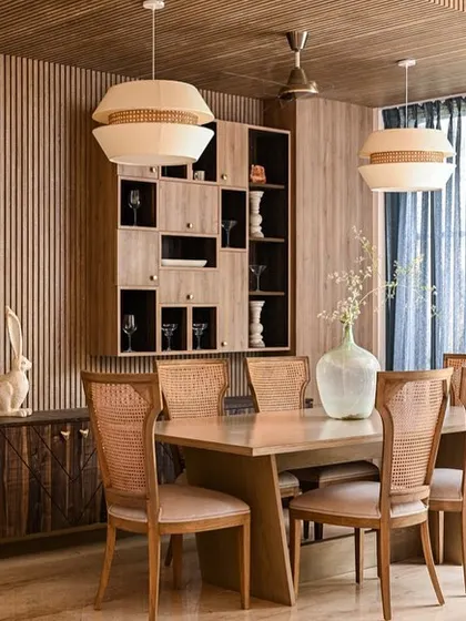 The "Anchorage 162" dining room, featuring wood-strip walls, a modern dining table, and cane-back chairs.