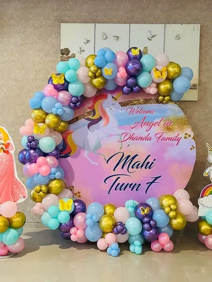 A magical unicorn and princess theme for Mahi's 7th birthday. This setup features a custom circular backdrop, character cutouts of princesses and unicorns, and a pastel and gold balloon arch.