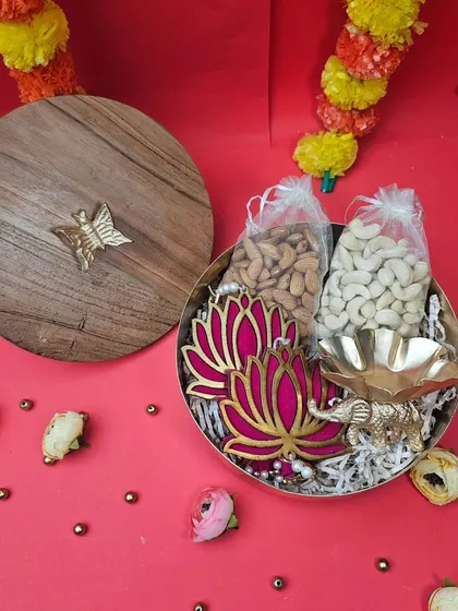 A sophisticated Diwali gift featuring a wooden-lid box. Inside, it holds dry fruits, a lotus-themed T-light holder, and an elephant diya, combining elegance with tradition.