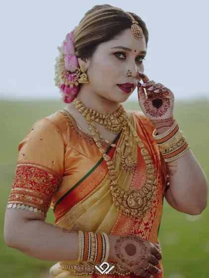 A classic bridal pose, showcasing the bride's traditional attire, heavy gold jewelry, and confident gaze.