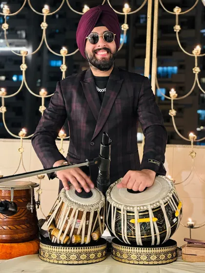 A formal shot of me with my tabla and dholak at a private event, set against a backdrop of beautiful festive lights.