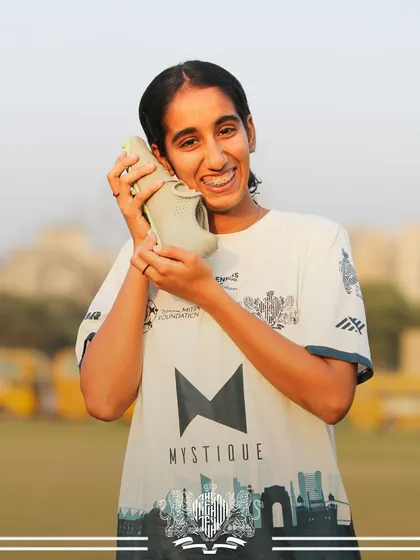 A lighthearted moment. A player playfully holds a shoe to her ear, showing the fun side of team life.