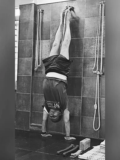 Practicing Adho Mukha Vrksasana (Handstand) with the support of wall ropes. The ropes provide safety and allow for a longer hold, helping to build shoulder strength and body awareness.