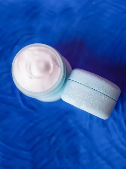 A top-down shot of the DHC moisturizer on a rich blue, furry texture. The contrast in color and texture makes the light blue product container pop.