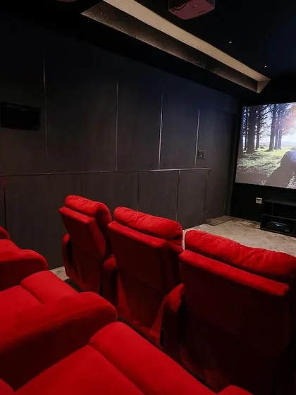 This shot shows the multiple rows of plush red recliners, creating a bold and dramatic look against the dark, acoustically treated walls.