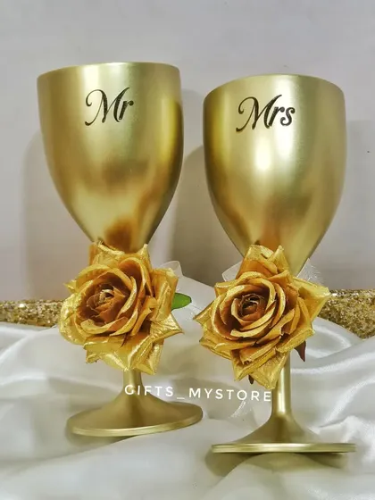 A pair of custom "Mr." and "Mrs." golden wine glasses, a perfect addition to any wedding or anniversary hamper.