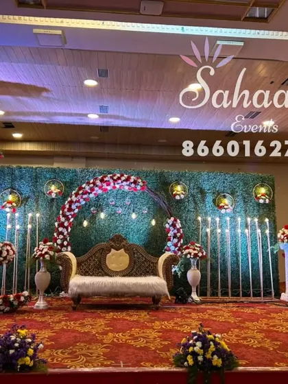 A grand stage setup for a naming ceremony. This design features multiple floral arches in a crescent moon shape against a green backdrop, creating a layered and impressive decoration.