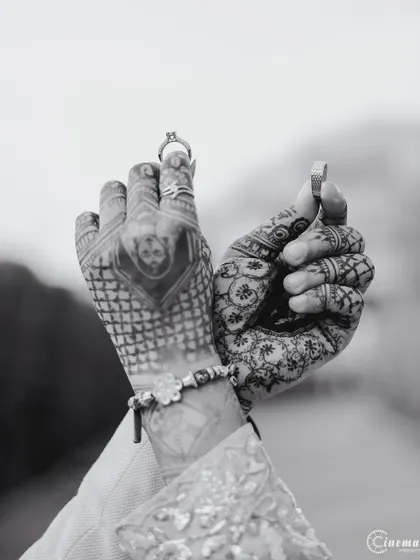 A creative black and white shot showcasing the couple's rings and the intricate henna designs on their hands, symbolizing their union.