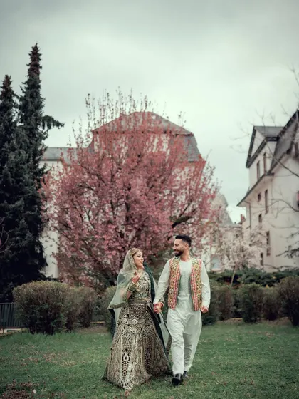 A couple walks hand-in-hand through a park after their wedding ceremony, enjoying their first moments as husband and wife.